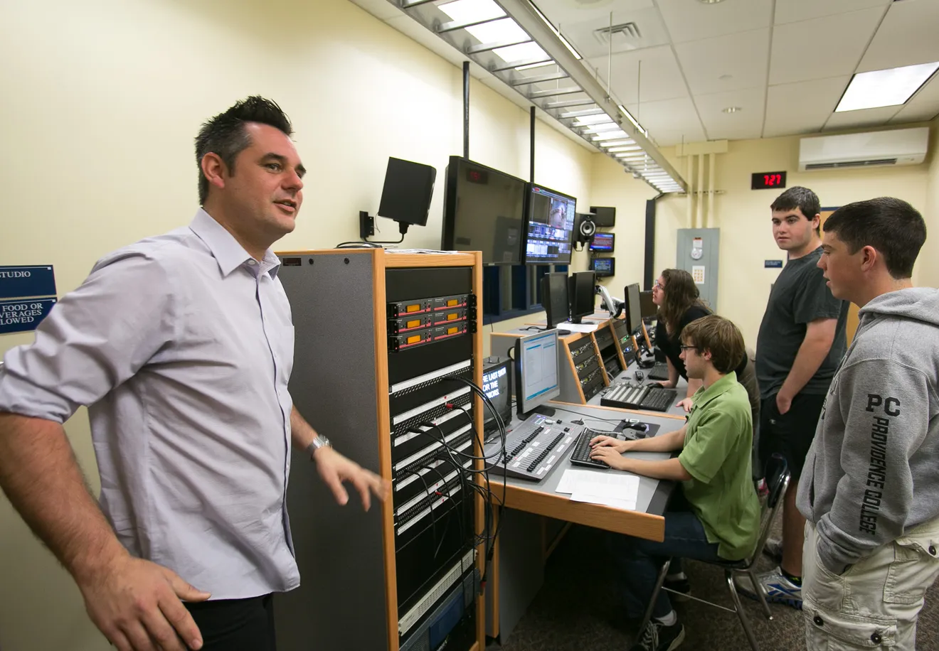 Founder Jeb Brunt working alongside students at a broadcast control desk